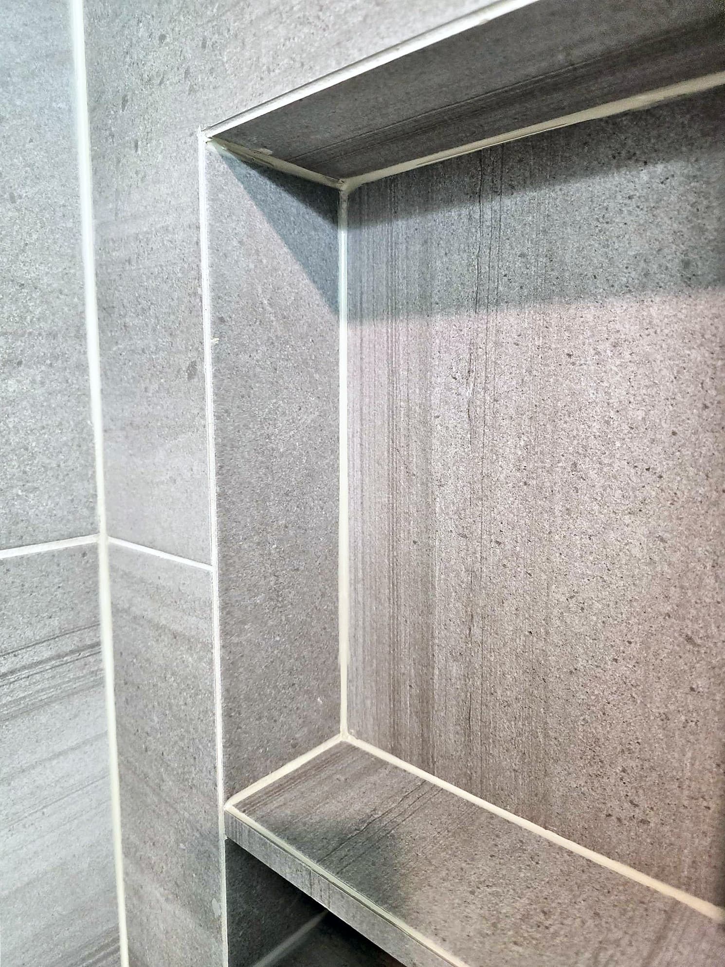 Close-up of a mitered tile corner at the top of a shower niche in Ambler