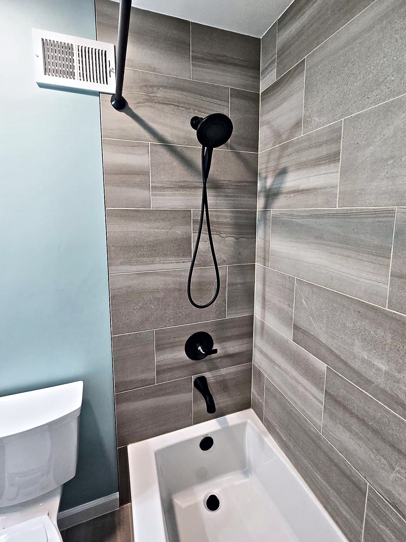 Low-sided tub with a matte black shower head, valve and spout in Ambler