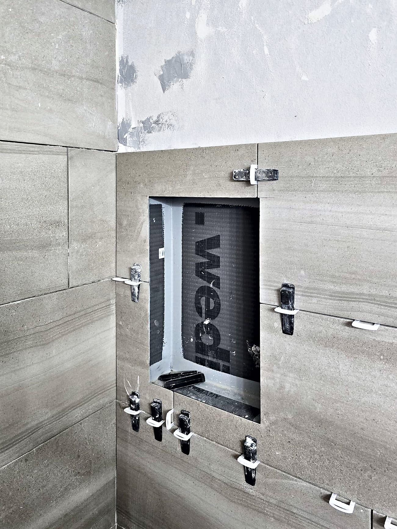 Tiling around the recessed shower niche during the Ambler bathroom remodel