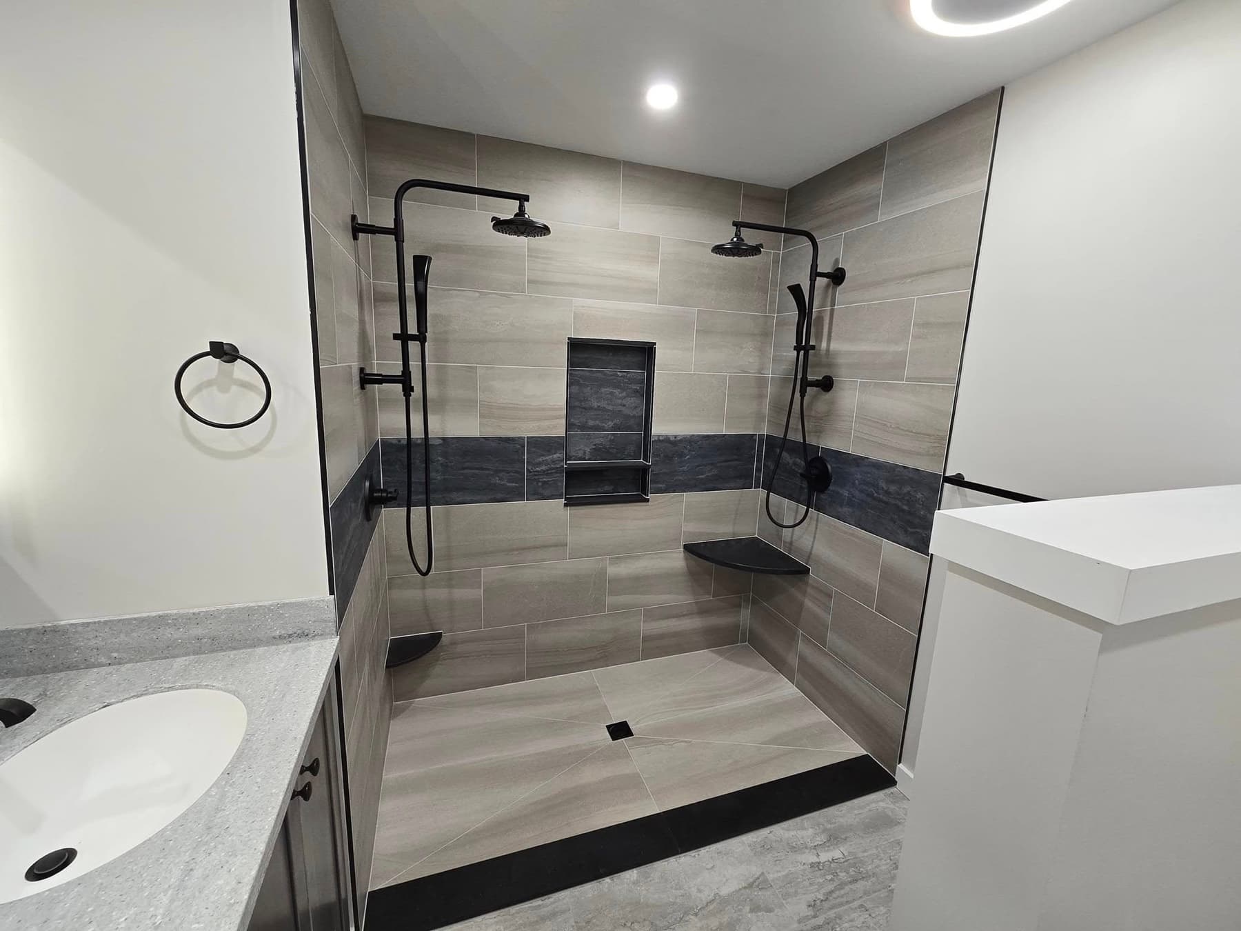 Tile walk-in shower with a dark accent band after a bathroom remodel in Buckingham