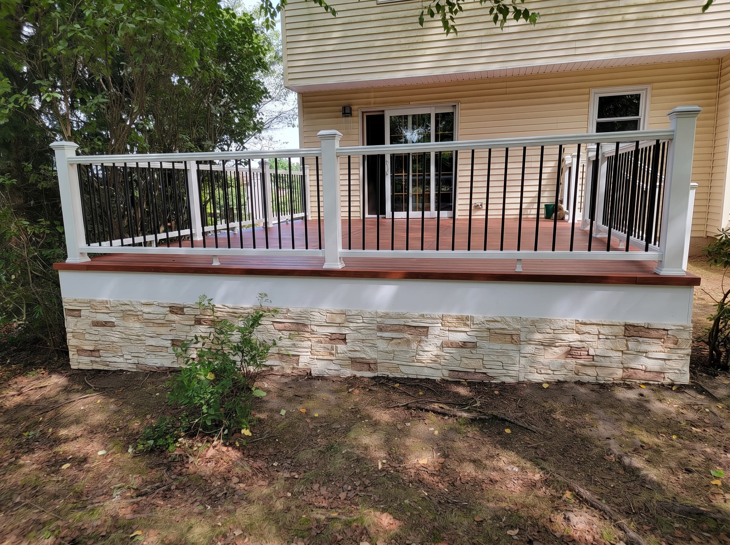Rebuilt raised deck with white railing and stone skirt in New Hope
