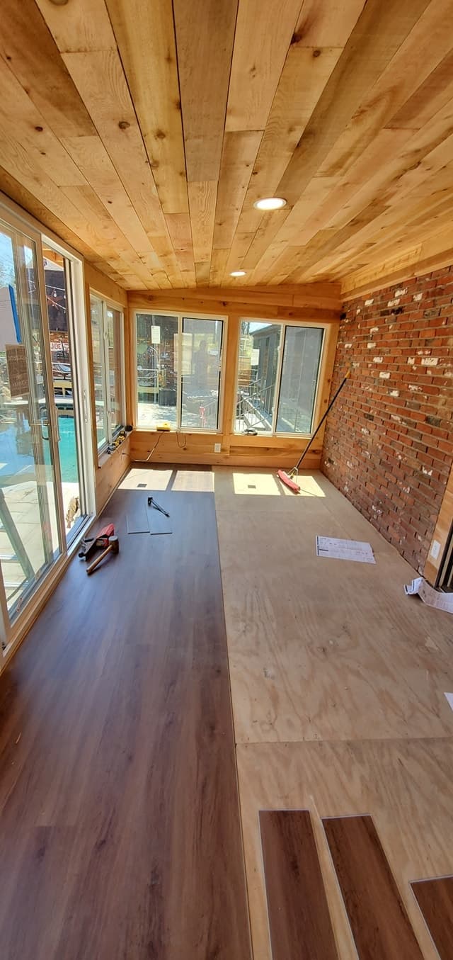 Sunroom addition with floor-to-ceiling windows and a deck view