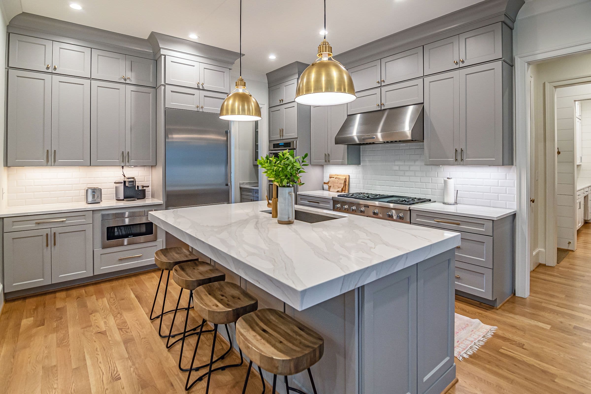 Kitchen Remodeling with Gray Cabinets and a Large Island Kitchen remodeling with gray shaker cabinets, a large white island, brass pendant lights and wood flooring