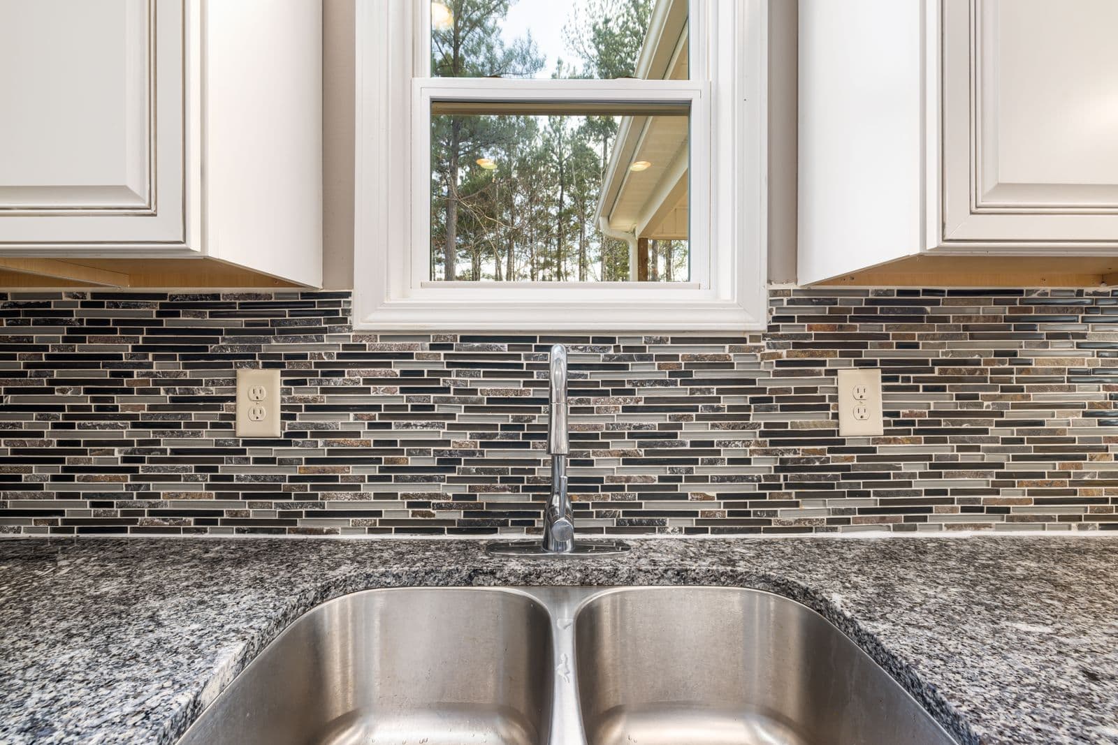 Glass mosaic tile backsplash behind a kitchen sink