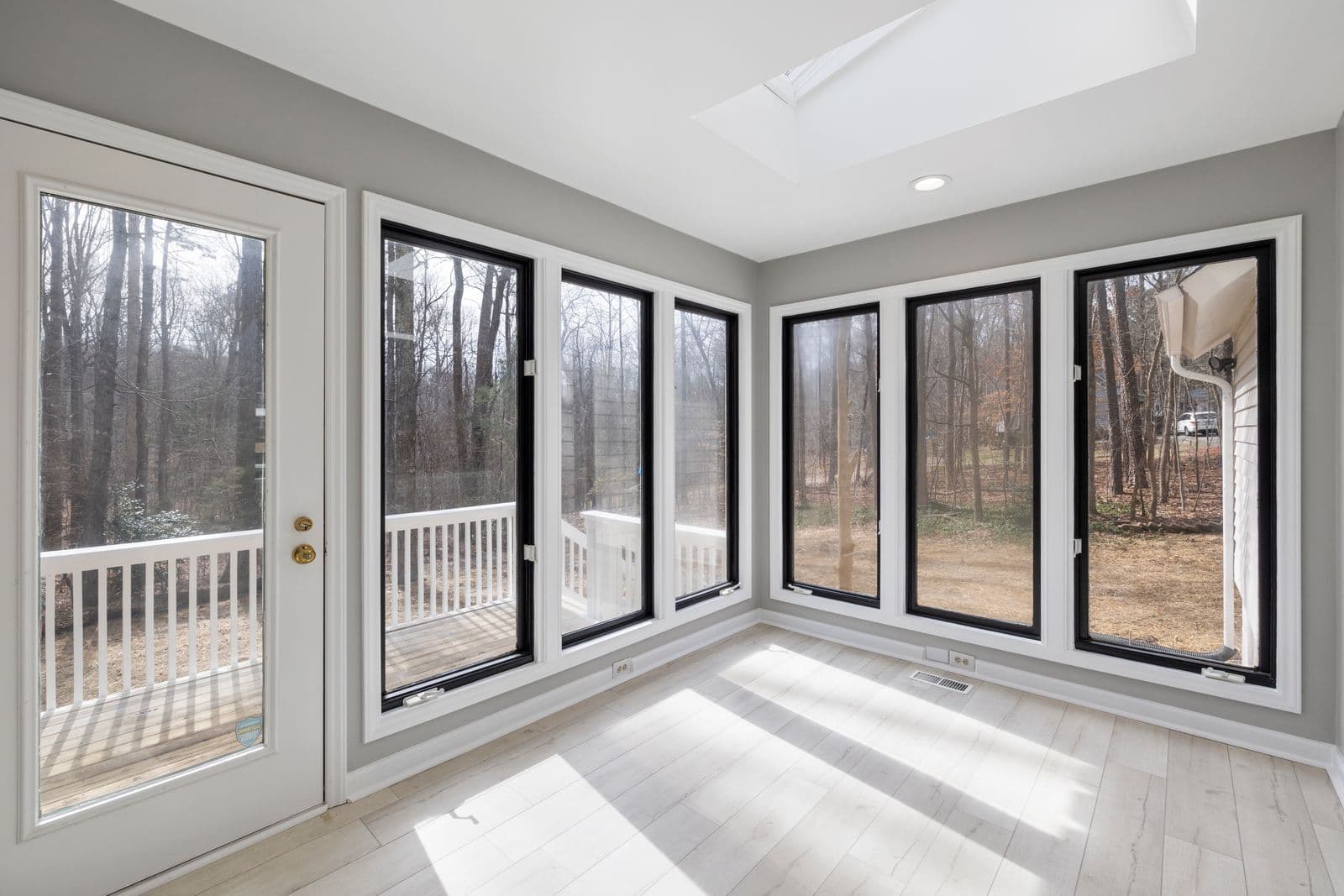 Sunroom addition with floor-to-ceiling windows and a deck view